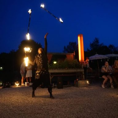 Feuerakrobat jongliert mit brennenden Fackeln bei Nacht.