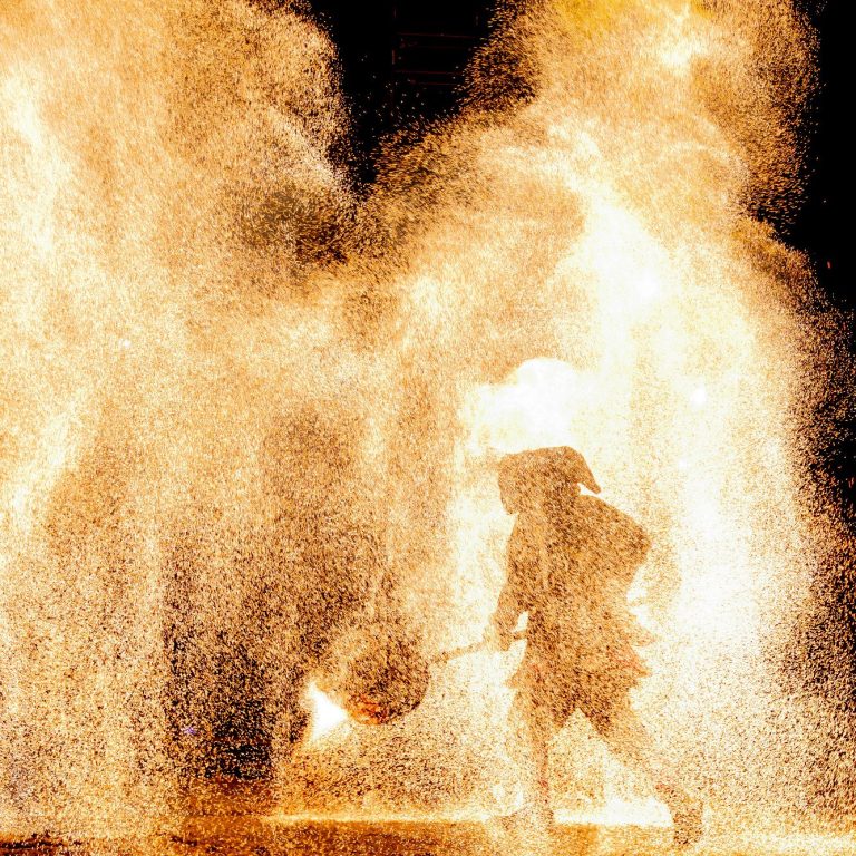 Feuerkünstler in Aktion, während er mit brennenden Stäben jongliert.