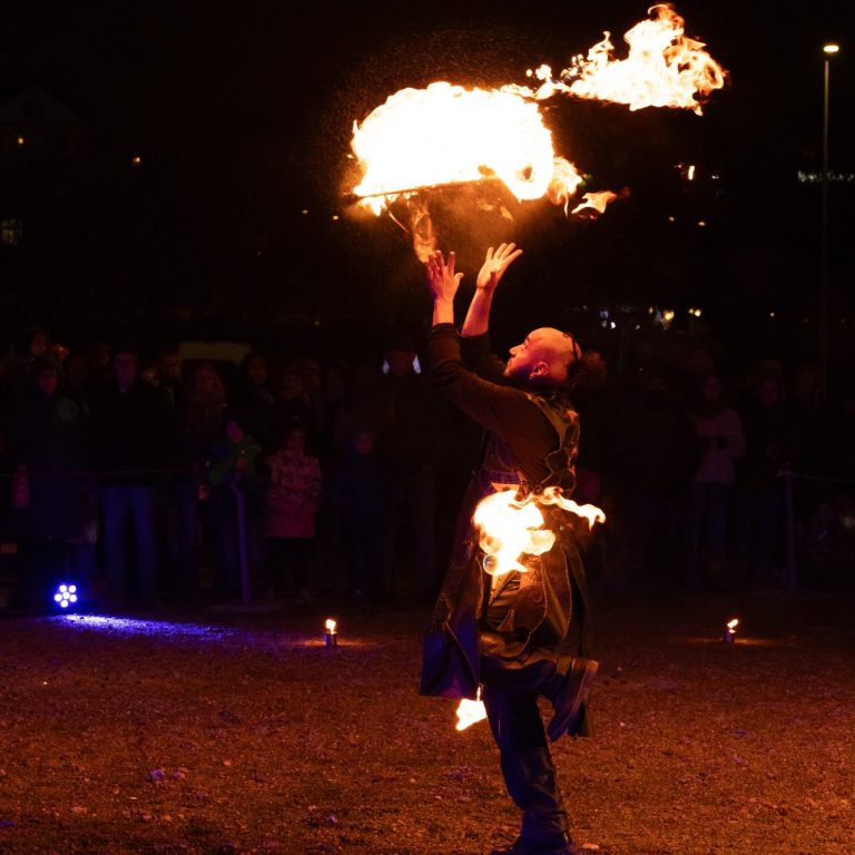 Feuerkünstler zeigt spektakuläre Show mit Flammen vor einer jubelnden Menge.