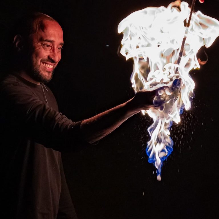 Mann mit brennendem Objekt, erzeugt spektakuläre Flammen und Lichtstrahlen.