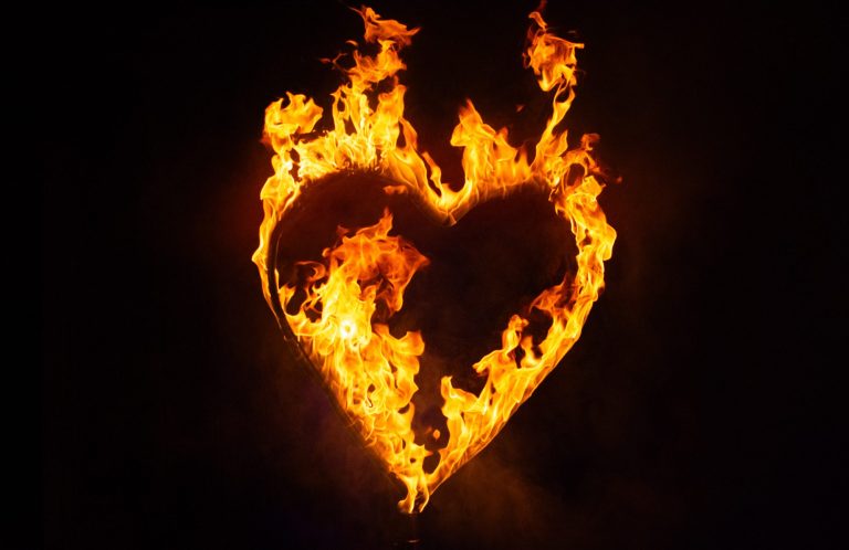 Flammen formen ein Herz vor einem schwarzen Hintergrund.